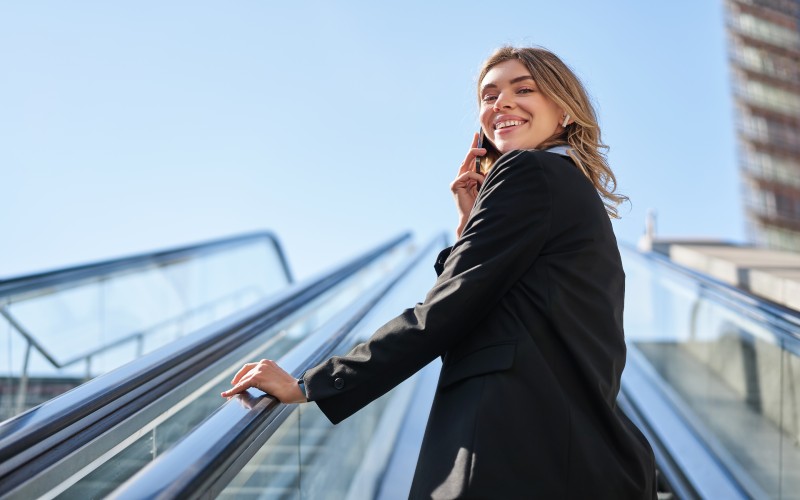 Portrait-businesswoman-black-suit-going-up-escalator-talking-mobile-phone-saleswoman-wal.jpg